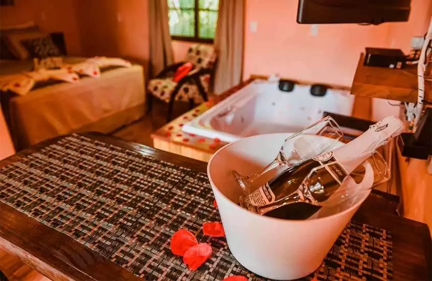 Chalé em Santa Catarina com cama de casal, poltrona, balde de champagne com taças, banheira de hidromassagem e televisão
