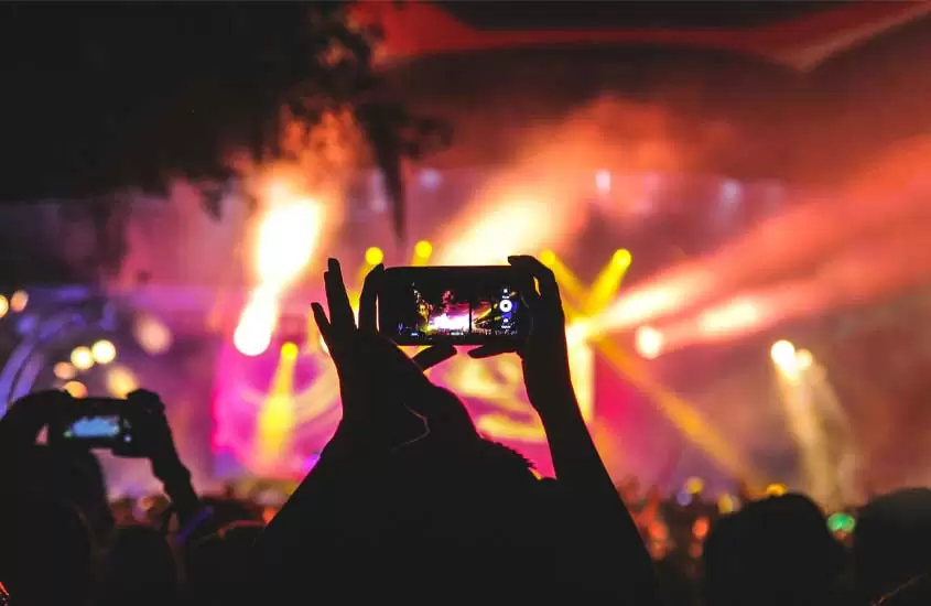 Durante a noite pessoas gravando com o celular um show em um dos festivais de música no brasil