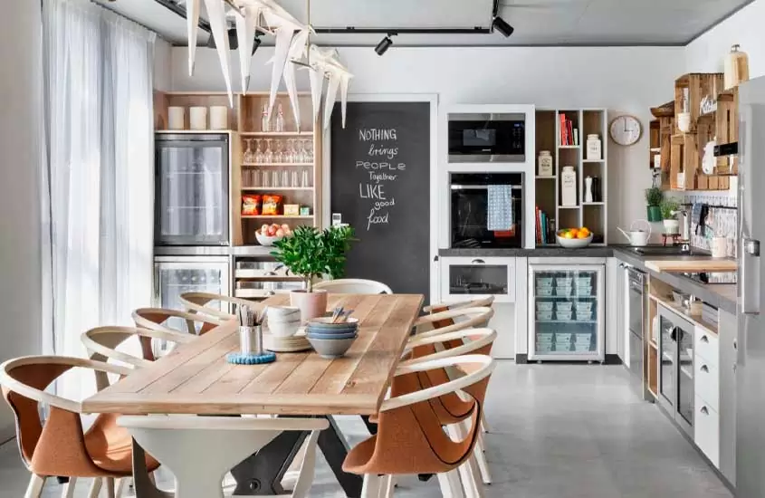 Mesa de jantar, eletrodomésticos e armários em cozinha de um dos apartamentos em Berna