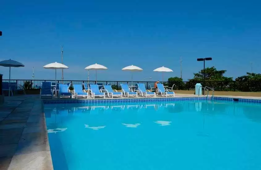 Durante um dia ensolarado, área de piscina de hotel na barra da tijuca beira-mar com piscina, espreguiçadeiras e guarda-sóis