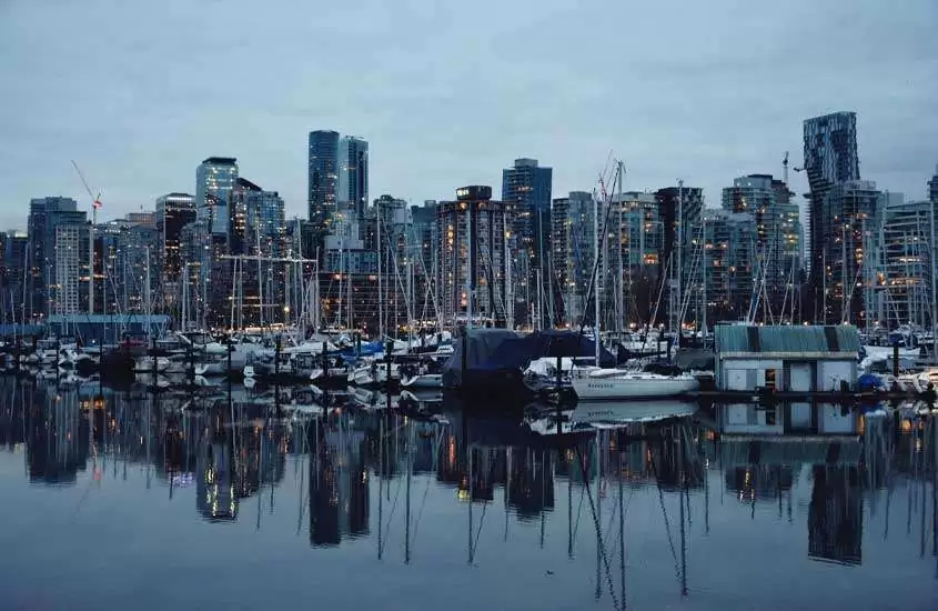 Em um dia nublado, diversos prédios às margens de porto com barcos em Coal Harbour, um bairro onde se hospedar em Vancouver