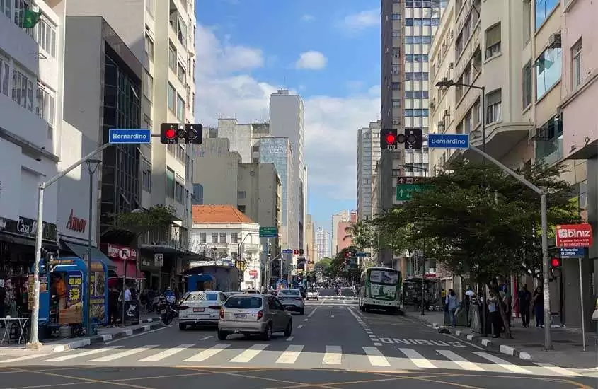 Centro de Campinas com carros, ônibus, árvores, pessoas transitando e prédios ao redor