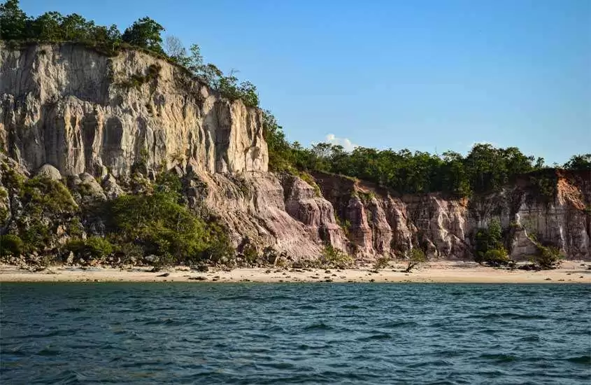 Em um dia de sol, praia em Alter do Chão, um lugares baratos para passar o ano novo com paredões de pedra e mar na frente