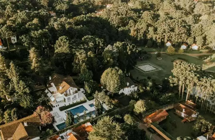 Em um dia de sol, vista aérea de um resort com árvores, piscina e parte gramada ao redor
