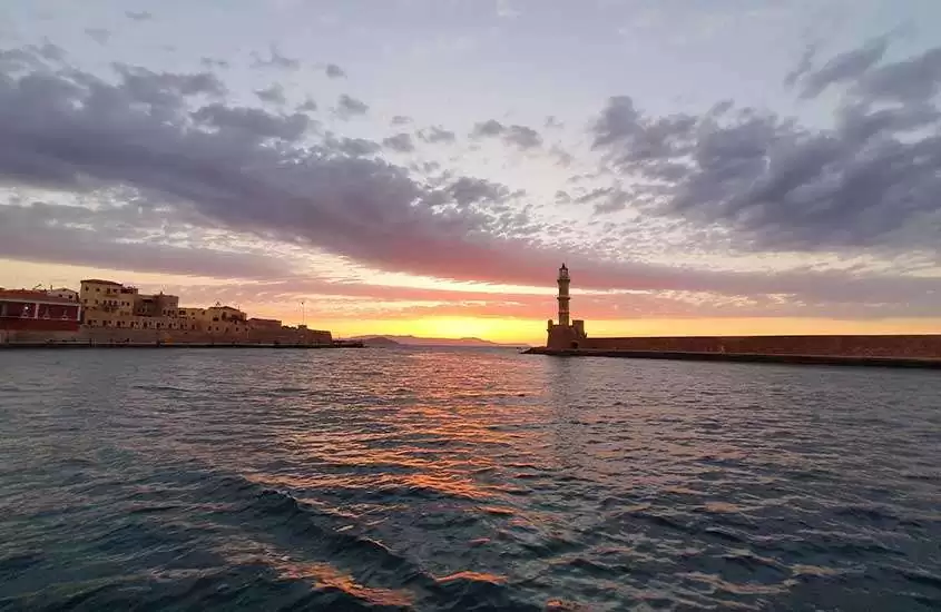 Durante o pôr do sol, vista do mar e da cidade no fundo com farol do lado