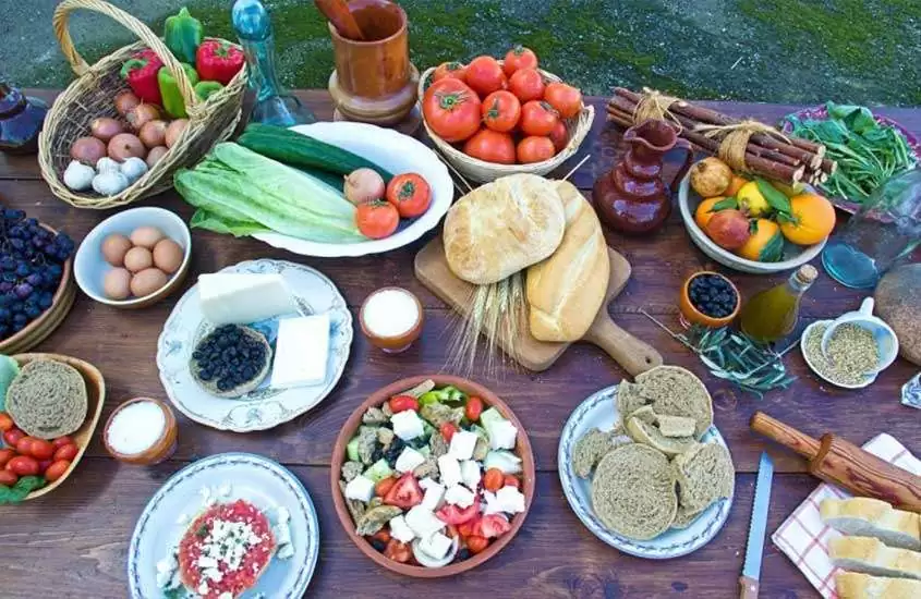 Mesa posta com pães, vegetais, frutas, temperos, saladas, azeites, queijos, ovos, etc