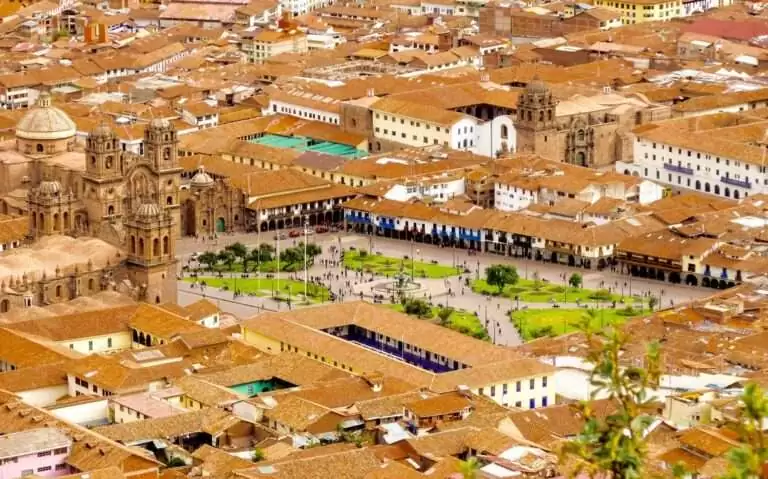 Em um dia ensolarado, vista aérea de Cusco com casas, construções, monumentos e praça no meio