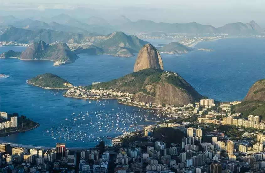 Em um dia de so, visão aérea do Rio de Janeiro, um dos lugares para viajar no feriado de corpus christi com pão de açúcar no meio, mar e cidade ao redor