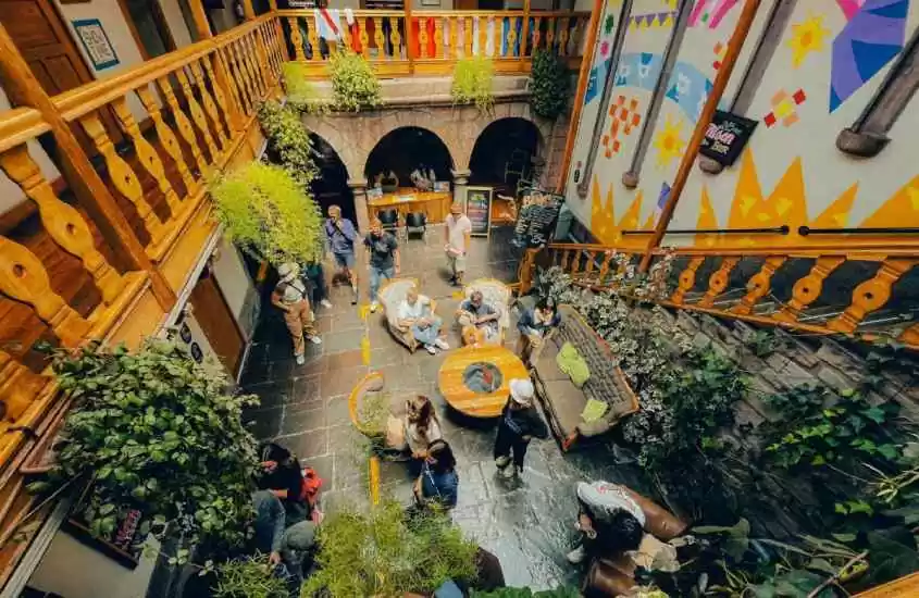 Vista aérea de um dos melhores hostels em Cusco com mesas, cadeiras, poltronas, sofás, plantas e flores ao redor