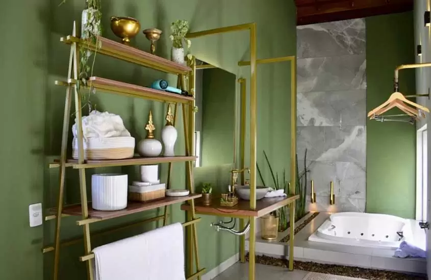 Banheiro de hotel com banheira, toalhas, decorações, plantas e cabideiro