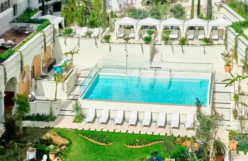 Vista aérea de área de lazer de um hotel onde ficar em Cannes França com piscina, tendas, jardim, espreguiçadeiras, mesas e cadeiras
