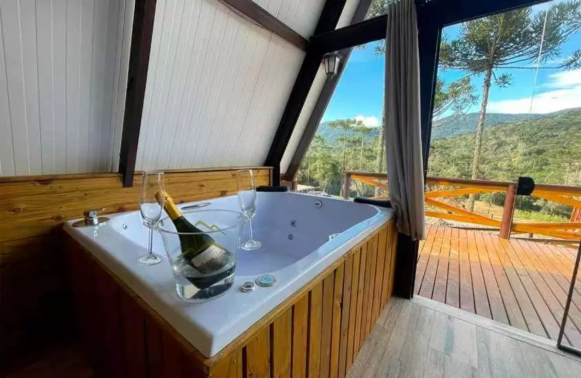 Banheira de uma das cabanas na Serra Catarinense com balde de champagne, deck de madeira e paisagem da serra na frente