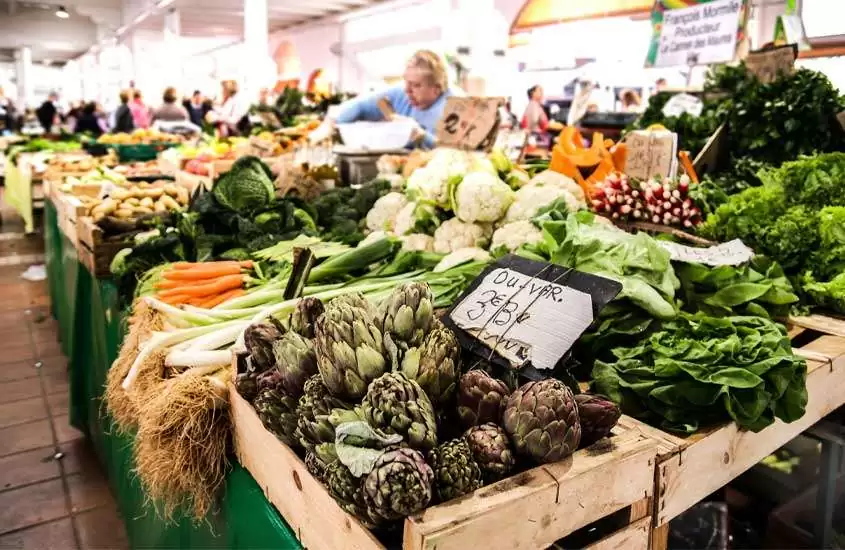 Mercado de vegetais e legumes com pessoas ao redor