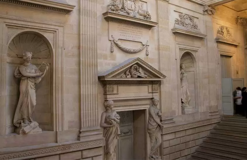 Interior de um dos pontos turísticos de bordeaux com esculturas ornamentais e pessoas do ado da escadaria