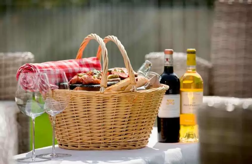 Cesta de picnic com vinhos, frios e toalha de mesa