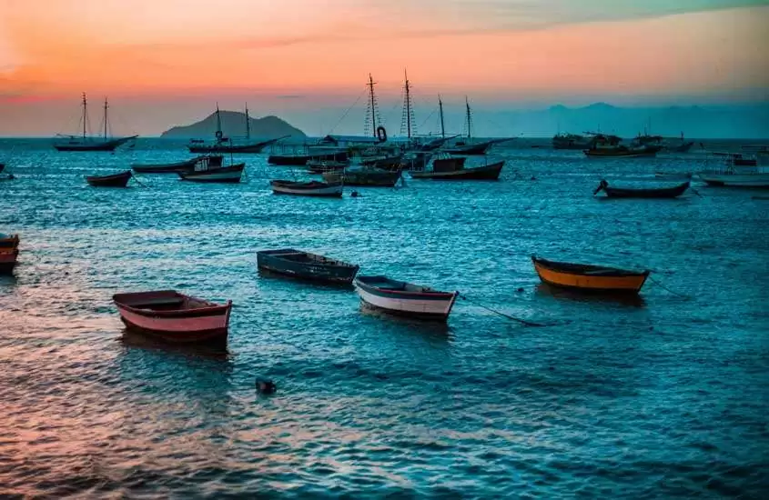 Durante o entardecer, mar com barcos aportados em Búzios